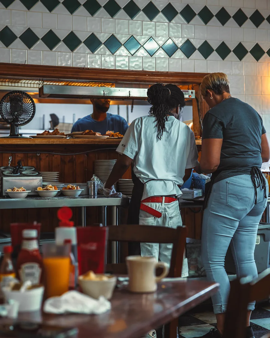 Two cooks working the line at a classic American diner, breakfast table set in the foreground