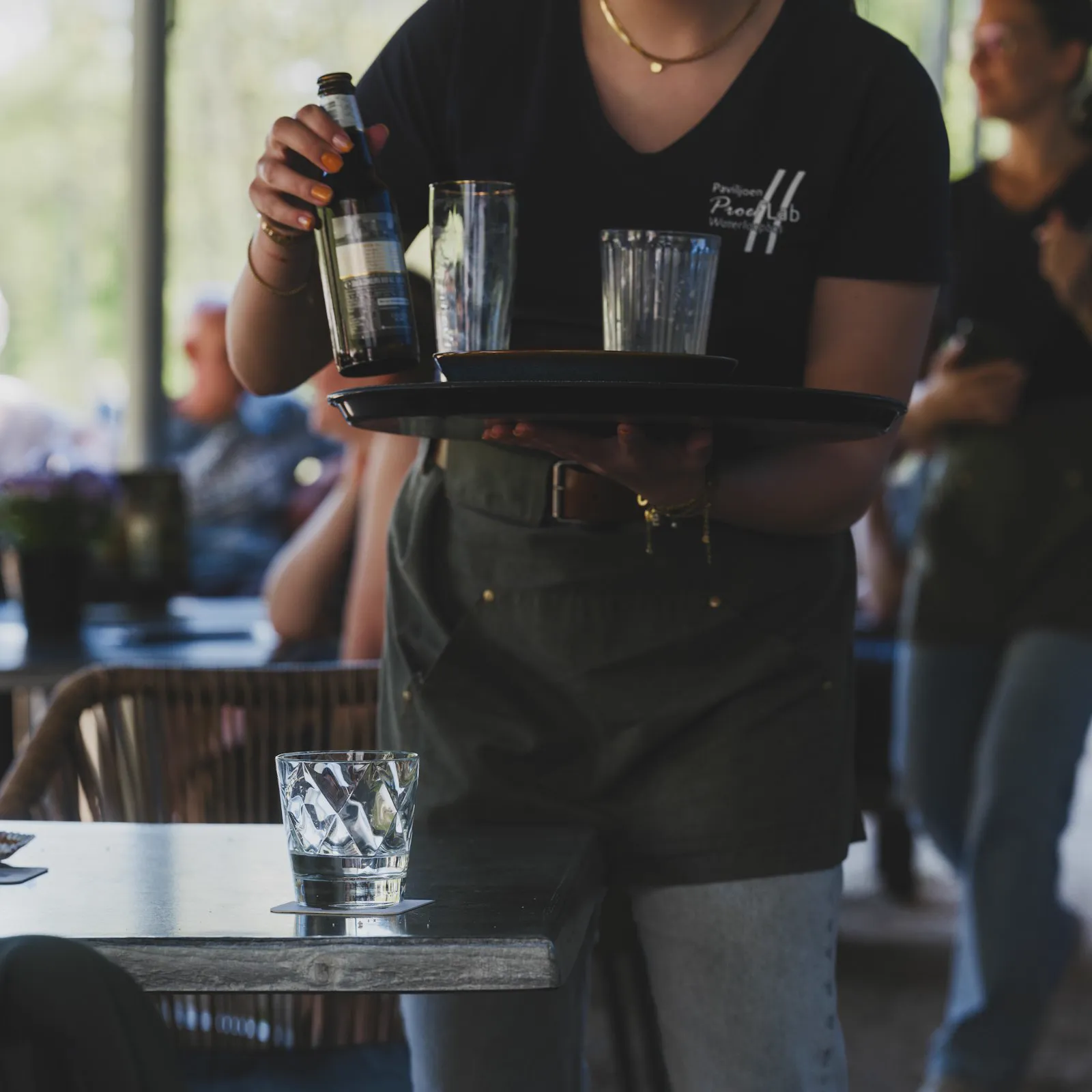 Server carrying a tray of drinks across a patio